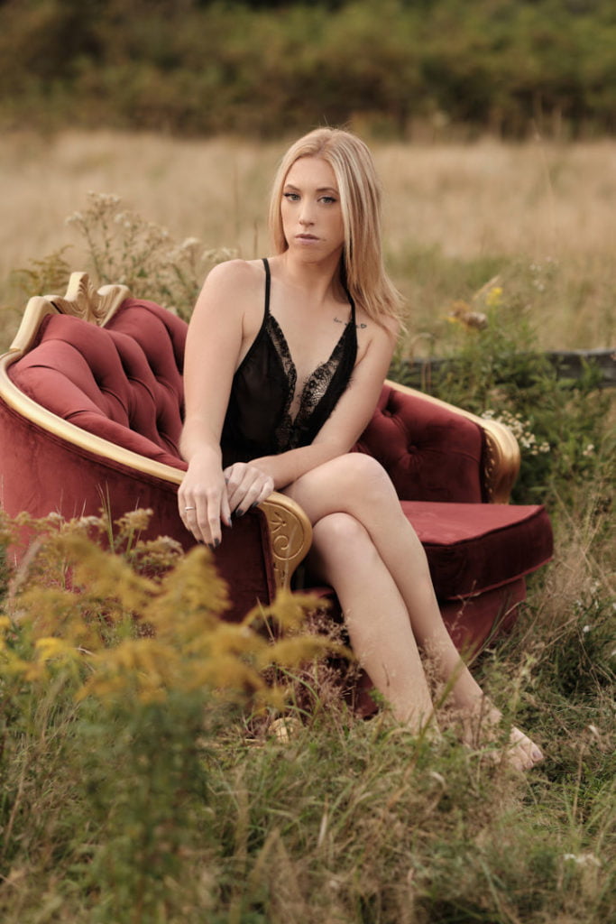 woman sitting in chair in field of grass black bodysuit lingerie blonde hair
