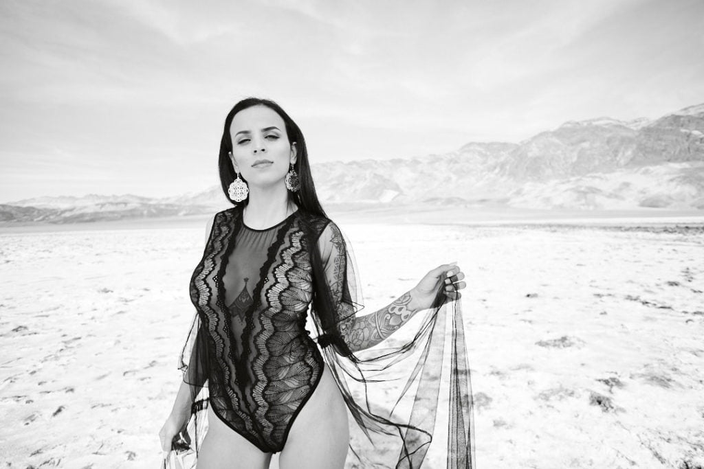 woman in black lingerie bodysuit and train in an open field black and white boudoir
