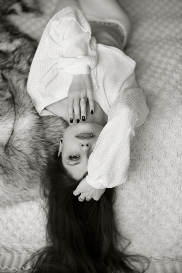 B&W shot of woman lying down in sweater for her toronto boudoir session