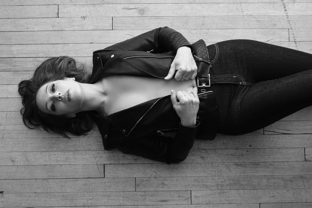 B&W photo of woman lying down on the floor in a leather jacket and jeans